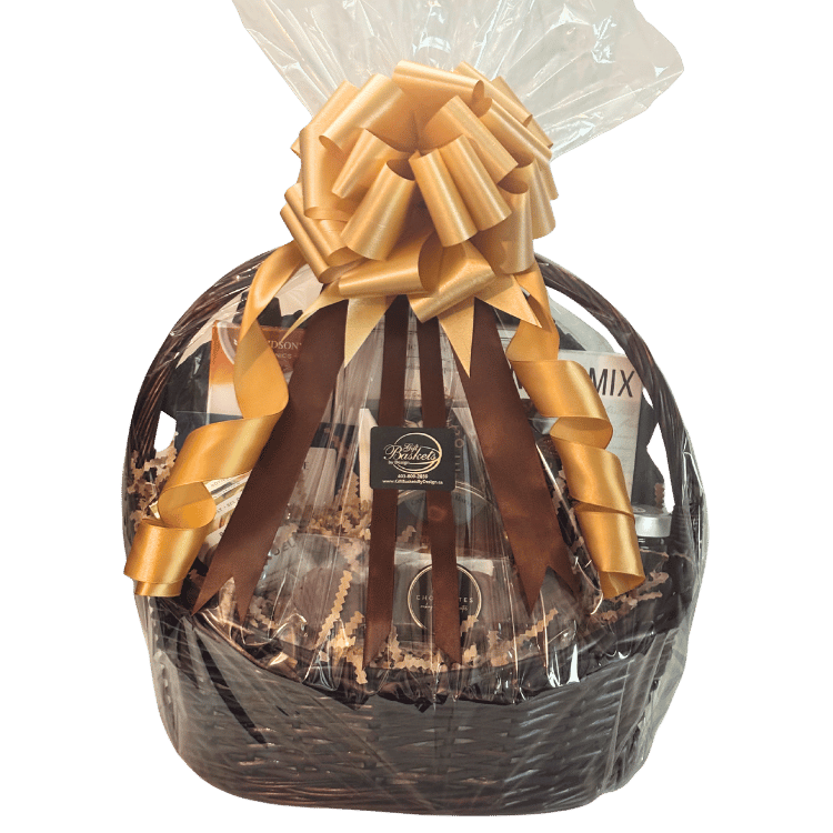 Gourmet Feast Gift basket handwrapped Calgary with clear cellophane, featuring a large golden-brown ribbon bow at the top, brown filler paper, and assorted packaged snacks and treats visible inside.
