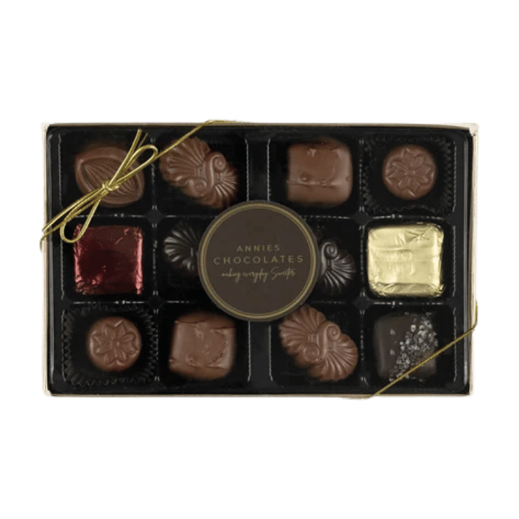 Annie's Chocolates chocolate box featuring 12 assorted chocolates in a black tray with a gold ribbon bow and a central round label, set against a plain white background.
