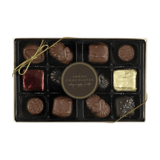 Annie's Chocolates chocolate box featuring 12 assorted chocolates in a black tray with a gold ribbon bow and a central round label, set against a plain white background.