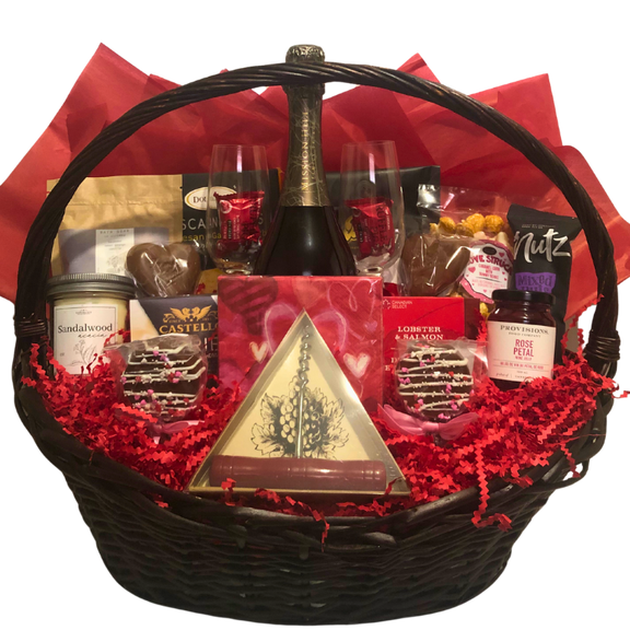 A gift basket containing various gourmet food items, spa items, wine and wine glasses, neatly arranged in a wicker basket with a beautiful red romantic colour scheme.