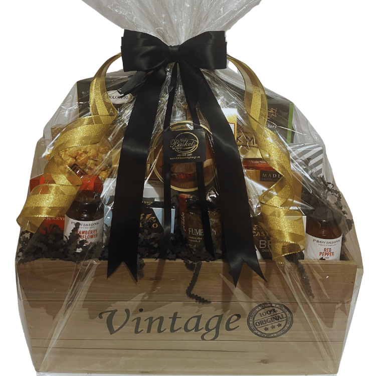 Vintage-style wood crate filled with gourmet snacks, cheese, chocolate, coffee, and savoury treats