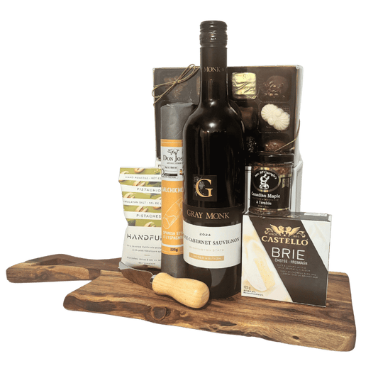 Good Company wine and charcuterie gift board with red wine, Brie cheese, artisan crackers, sausage, gourmet mustard, pistachios and chocolates on an acacia wood board.