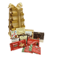 Elegant tower of golden gift boxes wrapped with shiny gold ribbons and bows, filled with gourmet treats including cookies, chocolate truffles, hot chocolate, and more, perfect for corporate gifting.
