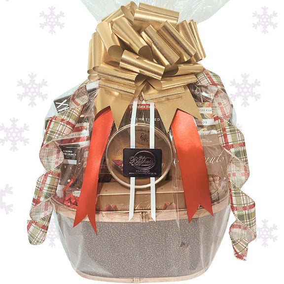 Holiday Gourmet Snacker gift basket with a gold bow and plaid ribbon on a white snowflake background