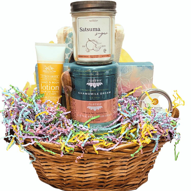A honey wicker basket featuring pastel-toned spa items, tea, candle, and chocolate bark.
