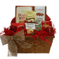 Elegant red holiday-themed gift basket filled with gourmet treats including peanut brittle, toffee peanuts, white chocolate cocoa mix, Lindor chocolate balls, chocolate chip shortbread cookies, hazelnut milk chocolate wafers, and holiday-flavoured teas.