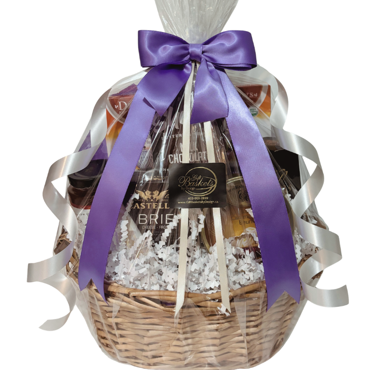 Afternoon tea gift basket with organic teas, artisan cheese, crackers, preserves, and sweets in golden wicker basket with purple and white ribbons and bow.