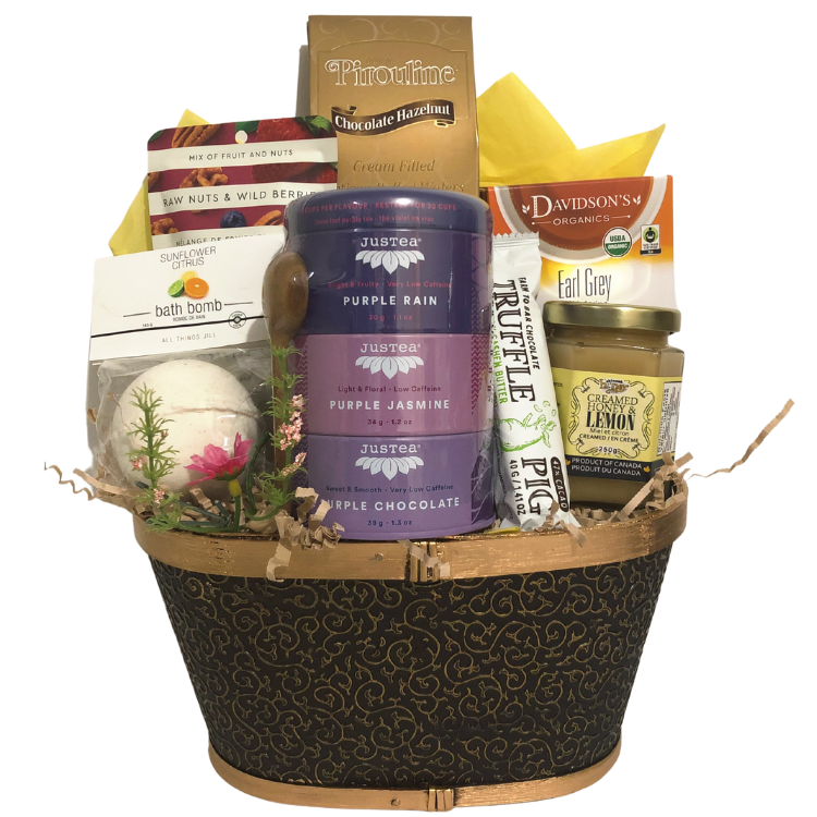 A calming gift basket featuring assorted teas, honey, a bath bomb, chocolate, and snacks, arranged in a black splitwood tray.